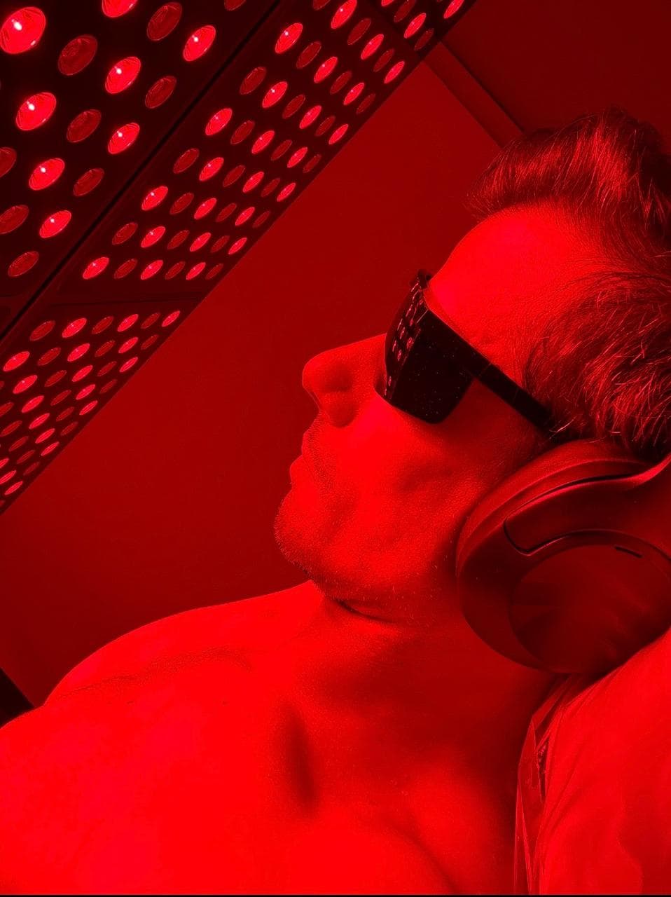 Sessão de fotobiomodulação com painel de LED vermelho próximo ao infravermelho e óculos de proteção